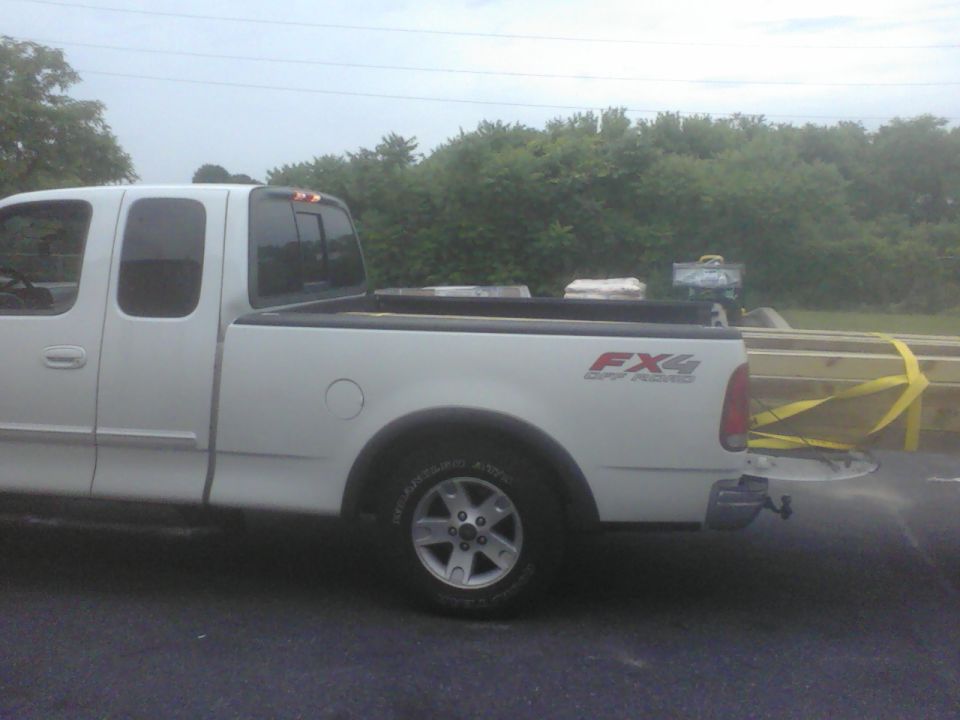 White pickup truck bed loaded with lumber, FX4 Off Road decal visible