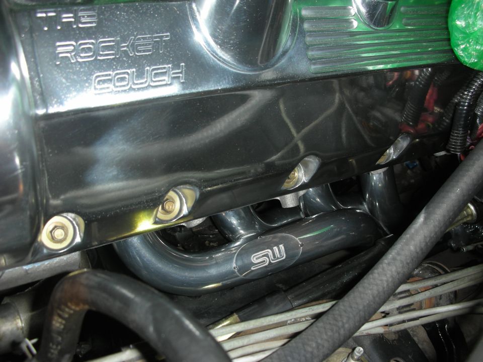 Chrome valve cover with "THE ROCKET COUCH" engraved, and exhaust headers with "SW" logo