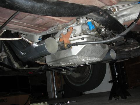 1992 Ford Crown Victoria - Underside view of a vehicle's transmission and custom exhaust system, likely during a rebuild or modification.