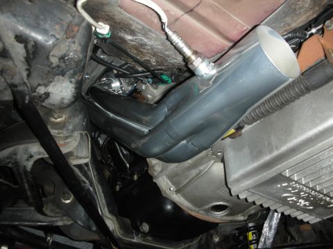1992 Ford Crown Victoria - Close-up of engine components, including exhaust headers and an oxygen sensor, under a vehicle.
