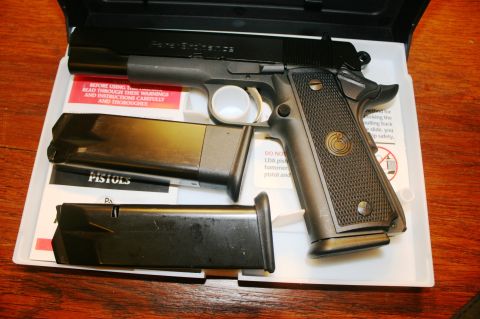 2006 Mazda 3 - A black semi-automatic pistol with two magazines is displayed in its case with instructional pamphlets.