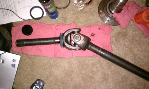 1990 Ford Bronco - A driveshaft with a U-joint is laid out on a pink cloth, with various tools and parts nearby.