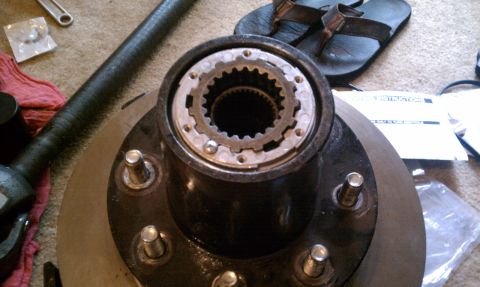 1990 Ford Bronco - A close-up of a vehicle hub assembly and brake rotor is shown on a carpeted surface, surrounded by tools.