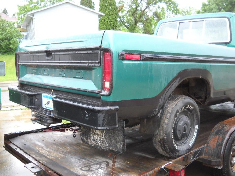 Rear of a teal Ford pickup truck with tailgate loaded on a trailer