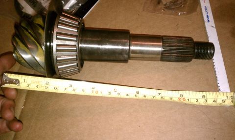 1990 Ford Bronco - A differential gear and axle shaft are shown with a measuring tape, indicating its dimensions.