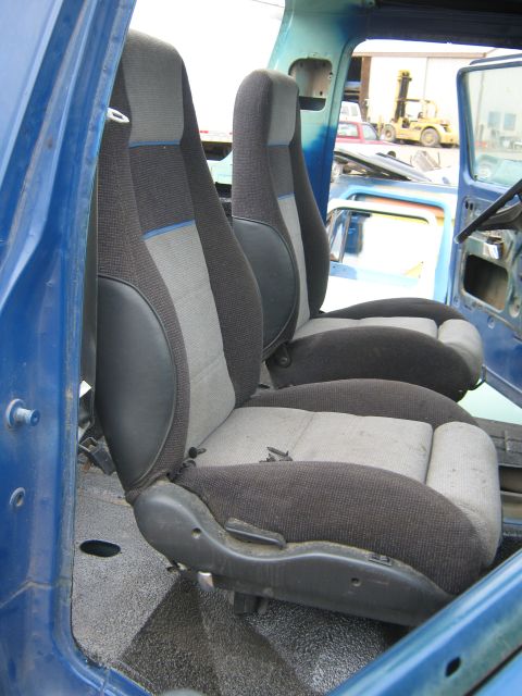 1978 Ford Bronco - The interior of a blue vehicle shows two-tone fabric seats with black bolsters and visible seat adjustment levers.