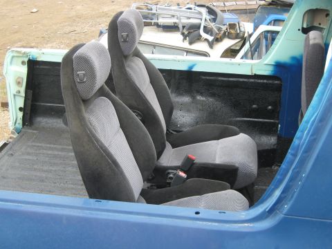 1978 Ford Bronco - The interior of a vehicle shows two front seats and the empty rear cargo area, with other vehicle parts visible in the background.