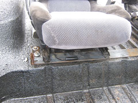 1978 Ford Bronco - Close-up of a vehicle's interior, focusing on seat mounting hardware and the textured floor surface.