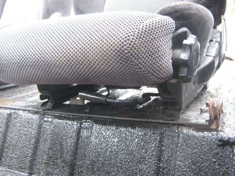 1978 Ford Bronco - A close-up view of a vehicle seat's mounting hardware and upholstery.