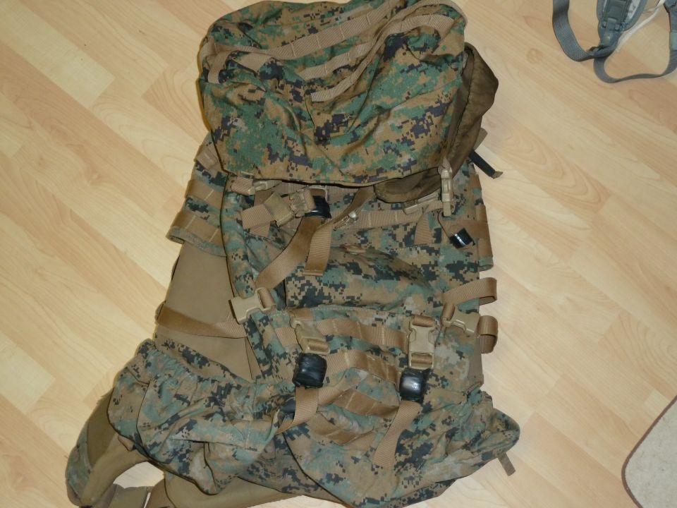 Camouflage military backpack with straps and buckles on a wooden floor