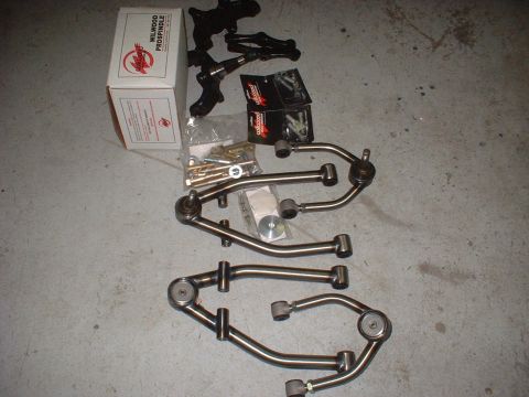 1969 Ford Torino - A collection of automotive suspension parts, including control arms and a Wilwood Pro-Spindle kit, laid out on a concrete floor.