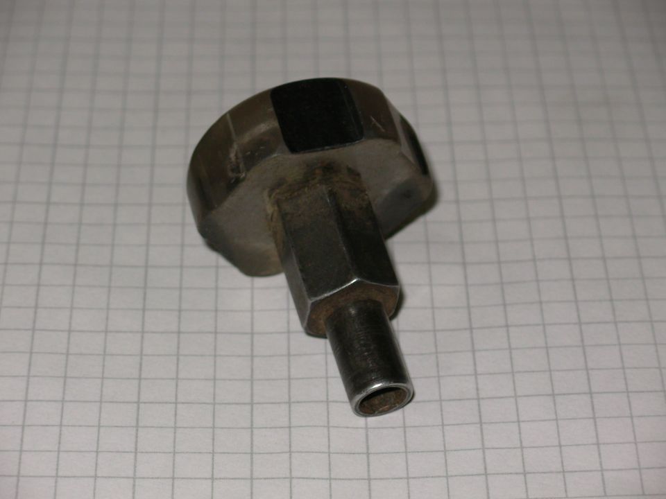 Hexagonal metal nut or fitting with a stepped shaft on graph paper