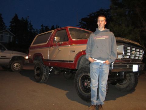 1984 Ford Bronco - Lifted 1980s Ford Bronco with a person posing in front. Another vehicle is visible to the left.