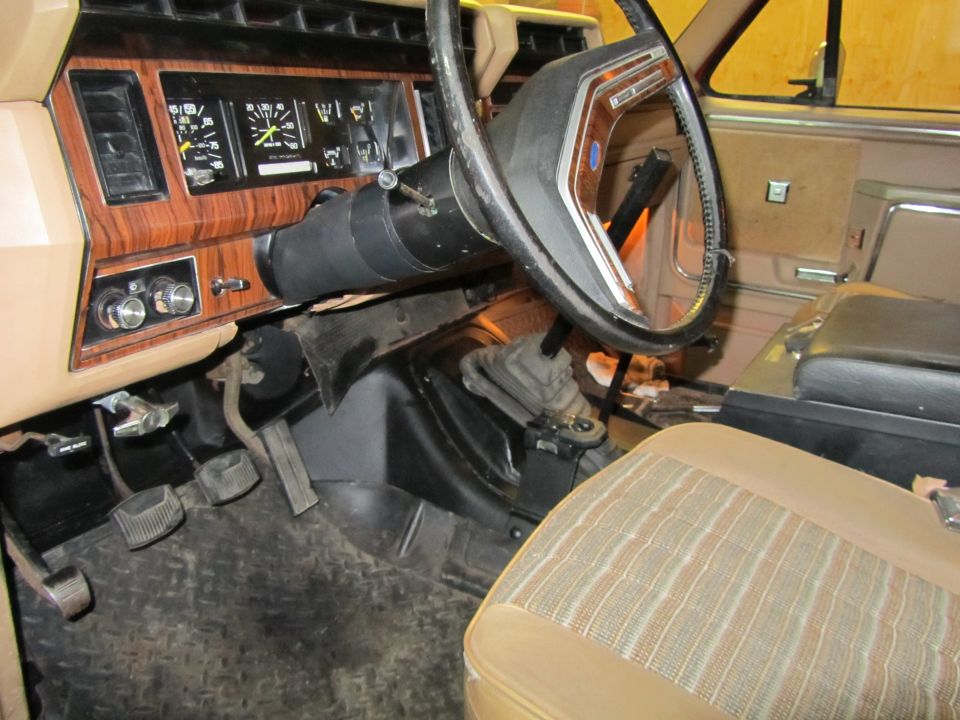 Interior view of a truck's dashboard, steering wheel, and seats. Shows gauges and gear shifter