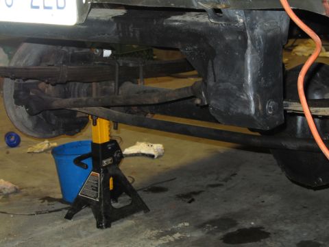 1984 Ford Bronco - Close-up view of a vehicle's undercarriage, showing leaf springs and a jack stand.