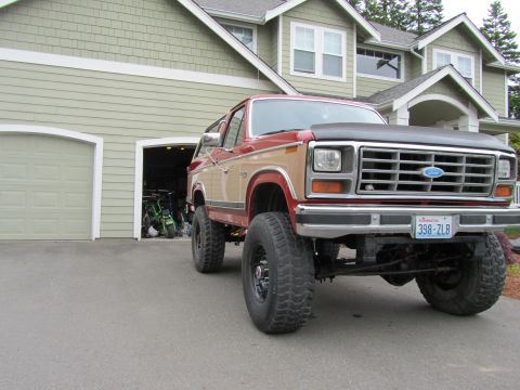 1984 Ford Bronco - This lifted Ford Bronco is parked in front of a residential garage, showing off its off-road tires and grille.