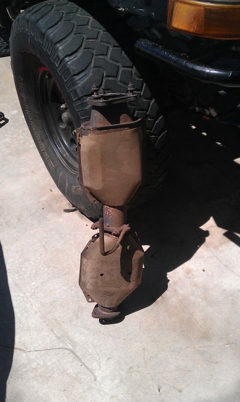 1992 Ford Ranger - A rusty exhaust component hangs precariously from the vehicle's chassis, near the wheel.