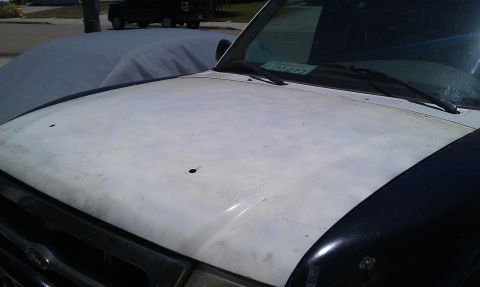 1992 Ford Ranger - The hood of a white Ford Ranger shows signs of wear and damage, with a black fender and windshield wipers visible.