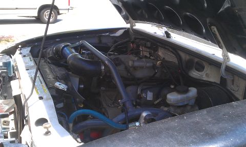 1992 Ford Ranger - The engine bay of a 1992 Ford Ranger shows an aftermarket intake system, with another vehicle visible in the background.