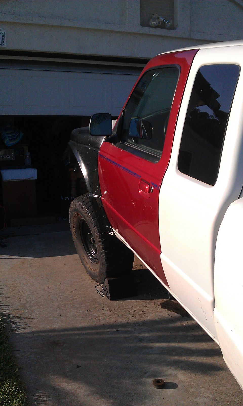 Red and white Ford Ranger truck side view, with mismatched front fender