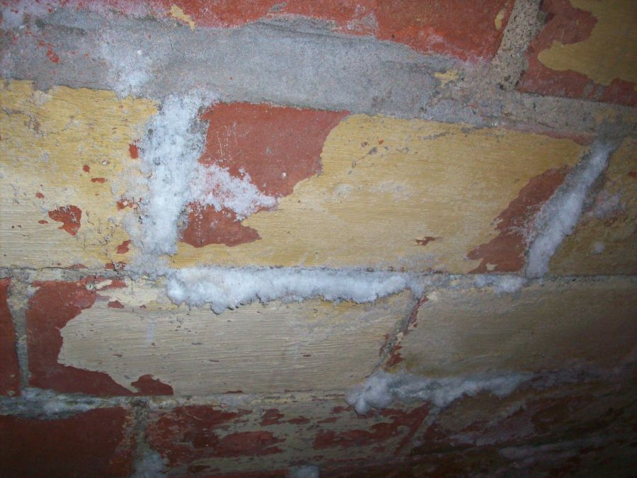 white powdery efflorescence on a weathered brick wall with red and yellow bricks