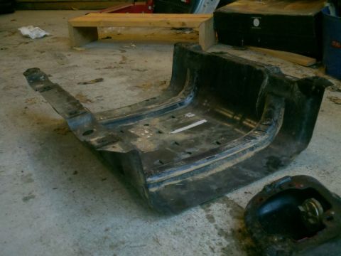 1979 Ford Bronco - This is a detached automotive part, possibly a skid plate or frame component, lying on a workshop floor.
