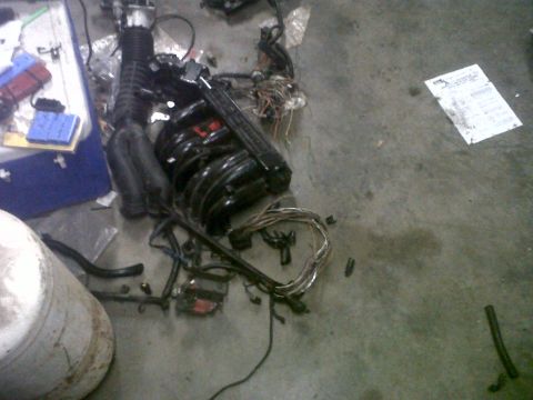 1994 Ford F-150 - Disassembled engine parts and wiring are laid out on the floor, with a document visible in the background.
