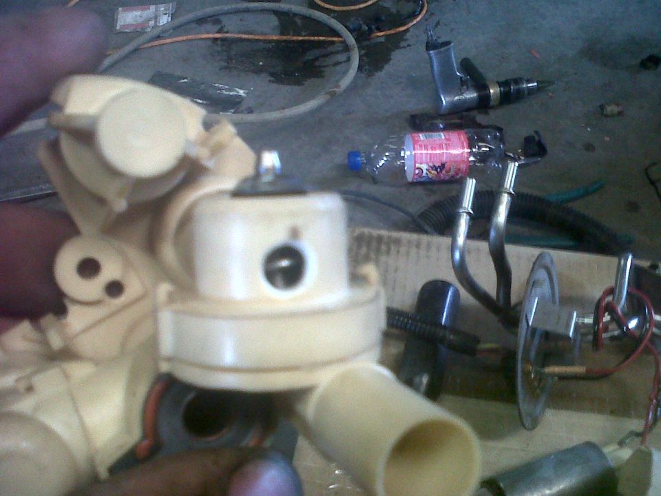 Cream-colored fuel pump assembly with metal lines and electrical connectors