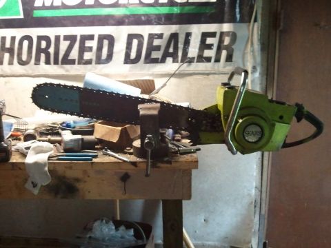 1985 Ford F-150 - A green Sears chainsaw is clamped in a vise on a workbench, surrounded by various tools.