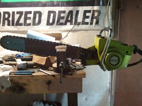 1985 Ford F-150 - A Sears chainsaw is clamped in a vise on a workbench, surrounded by tools and supplies.