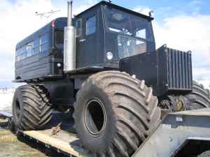 1987 Suzuki Samurai - This large, dark-colored all-terrain vehicle is seen from a 3/4 front view while on a flatbed trailer.