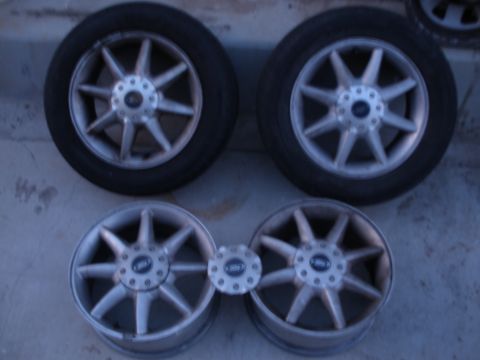 1998 Ford Contour - A set of four alloy rims with tires are laid out on a surface. Two rims have tires mounted, and two are bare.