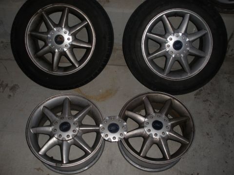 1998 Ford Contour - Four silver Ford rims with tires are displayed, along with two matching center caps.