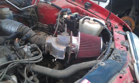 1991 Ford Festiva - Close-up view of a car's engine bay, showing an aftermarket air intake system and various engine parts.