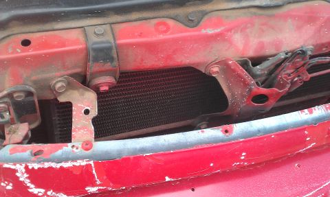 1991 Ford Festiva - Close-up of the front grille support and radiator of a red 1991 Ford Festiva.