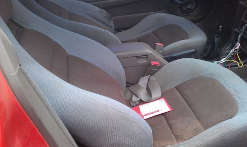 1991 Ford Festiva - The interior of a vehicle shows two rows of gray and brown fabric seats, with a red tag visible on the passenger seat.