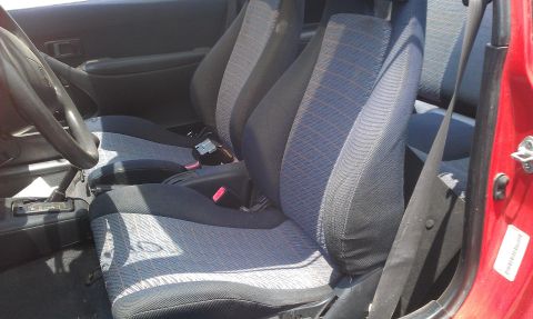 1991 Ford Festiva - The interior of a red 1991 Ford Festiva shows its patterned cloth seats and dashboard details.