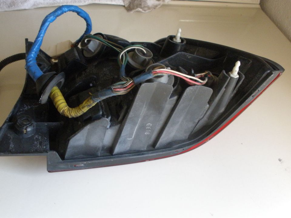 Rear of a car tail light assembly with wiring harness and mounting posts