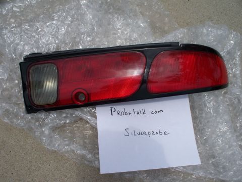 1994 Ford Probe - A single car taillight is shown, resting on bubble wrap. Text on a paper below identifies it as a ProbeTalk.com item.