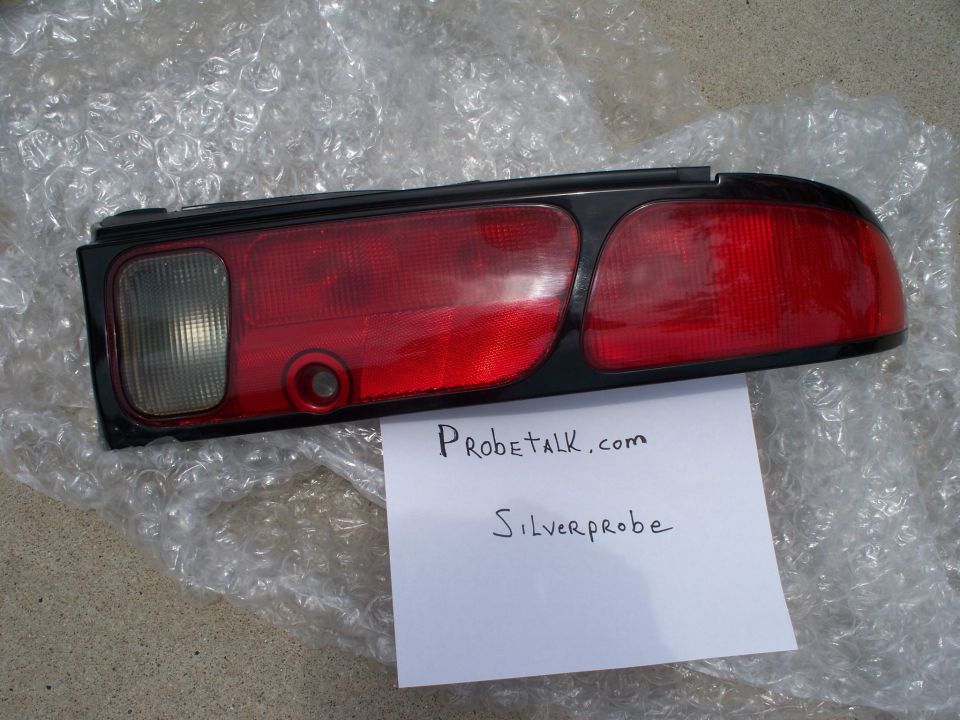 Car taillight assembly with red and clear lenses. Paper with "Probetalk.com" and "Silverprobe" written on it is placed underneath