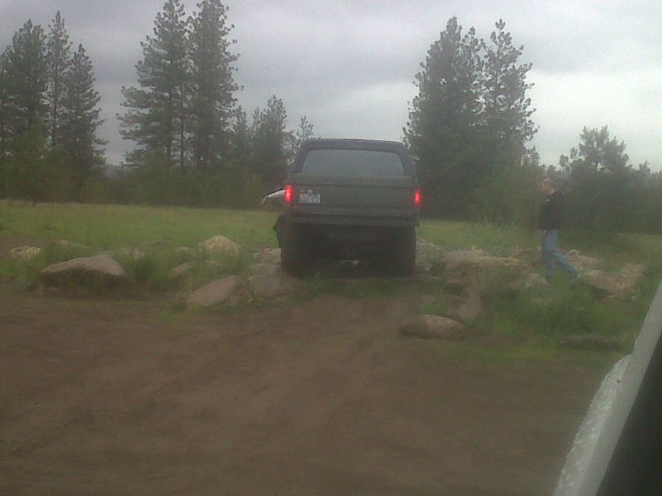 Dark pickup truck crossing rocks on a dirt off-road area