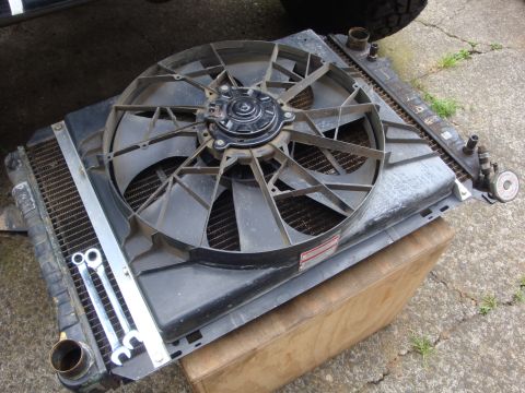 1989 Ford Bronco - A radiator and fan assembly is shown, with two wrenches placed on its side.