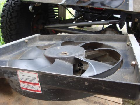 1989 Ford Bronco - A radiator fan is shown in the foreground, with the suspension and a large tire of a lifted vehicle visible in the background.