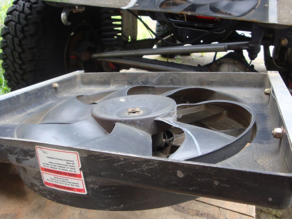 Radiator fan in foreground, with suspension and tire of a lifted vehicle behind
