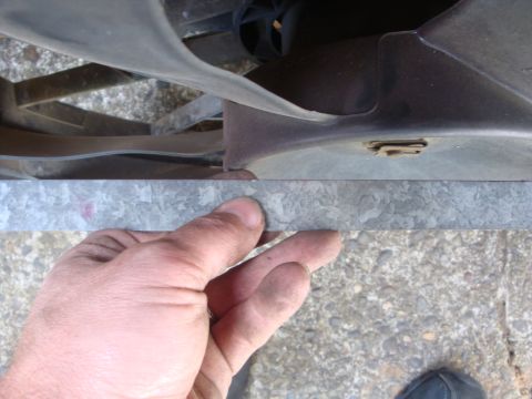 1989 Ford Bronco - Close-up of a hand touching the fan shroud of an engine compartment.