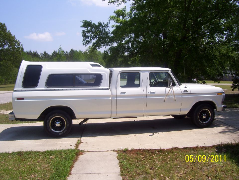 White 1978 Ford F-350 crew cab pickup with a white camper shell on the bed, parked on a driveway