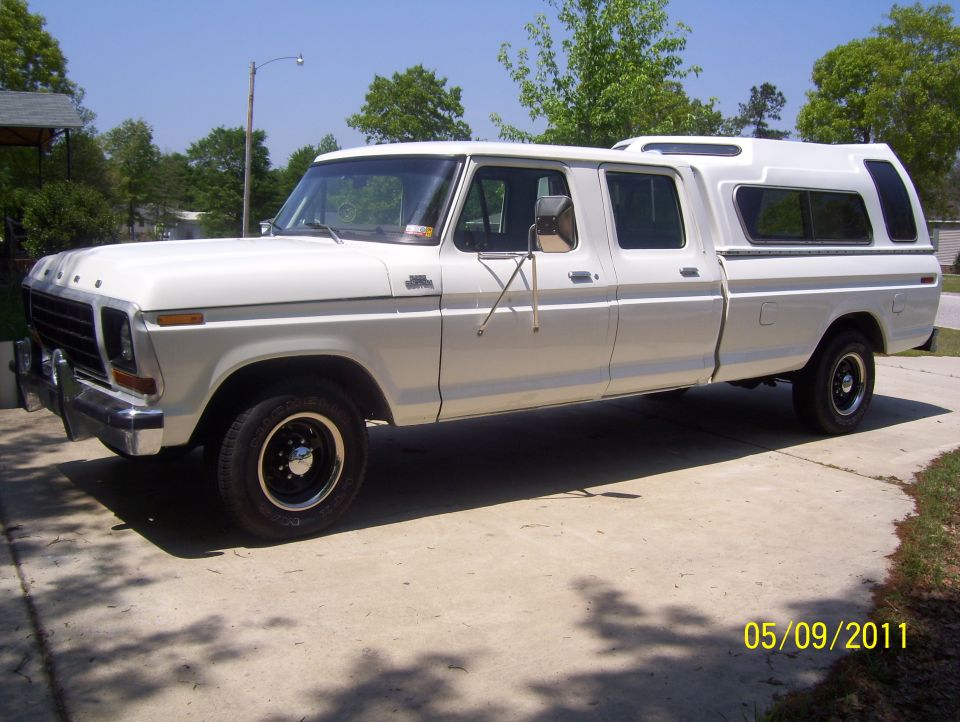 White 1978 Ford F-350 crew cab pickup truck with camper shell, side view