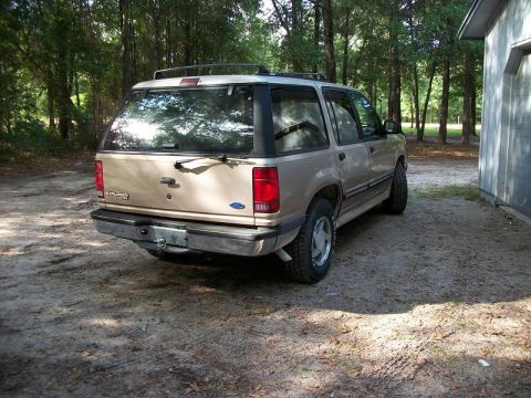 1994 Ford Explorer - Rear view of a 1994 Ford Explorer SUV parked outdoors near a wooded area and a garage.