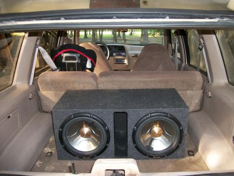 1994 Ford Explorer - The rear cargo area of a 1994 Ford Explorer contains a dual subwoofer box and a child seat.