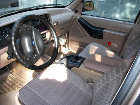 1994 Ford Explorer - The interior of a 1994 Ford Explorer shows tan cloth seats and a dashboard with a steering wheel.